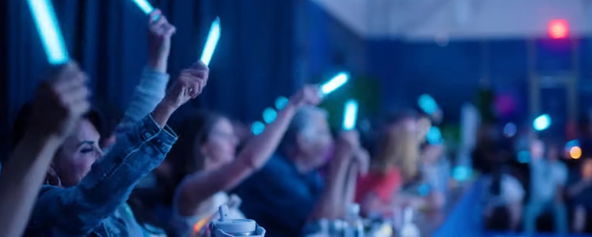 Crowd of people waving blue lights in celebration of a Tuesday Night Pickleball events.