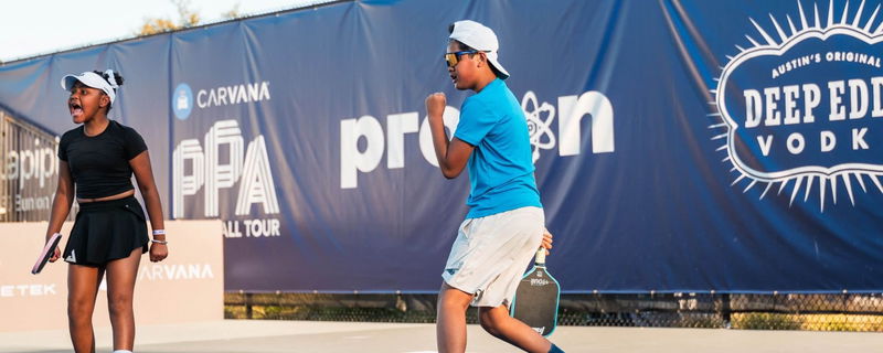 A girl and boy celebrating on the pickleball court.