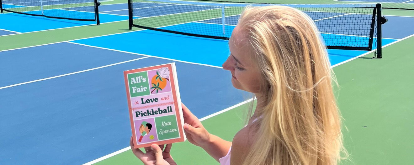 Woman reading a pickleball romance book by the pickleball court.