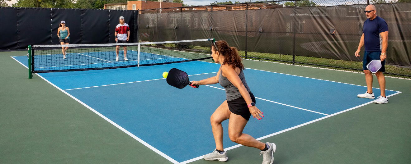 A woman returning a serve on a pickleball court.