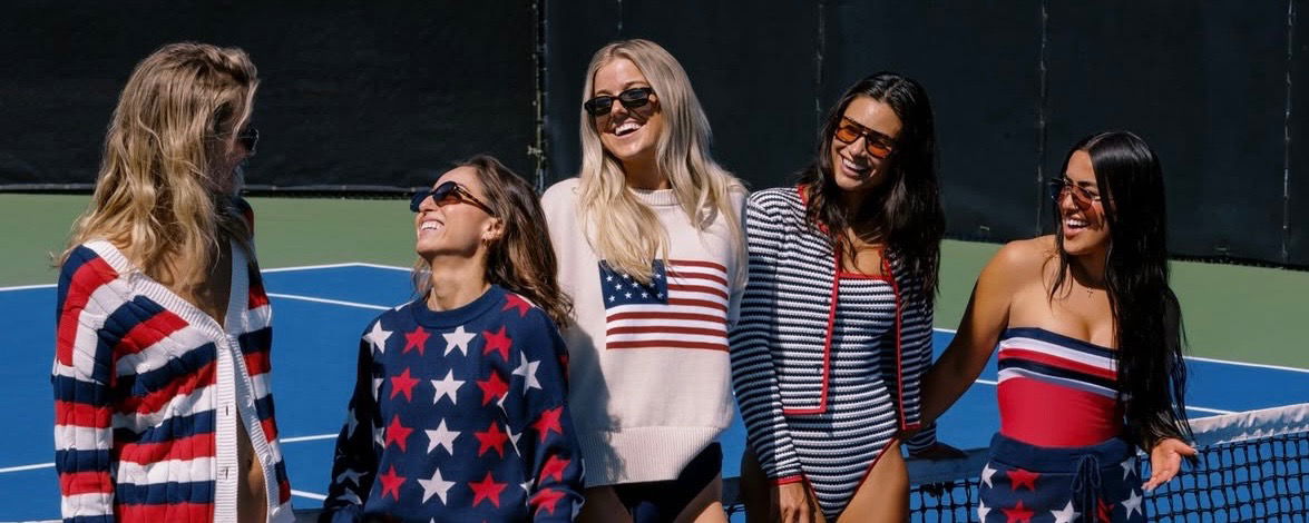 Five women in red white and blue sweaters standing on a court.