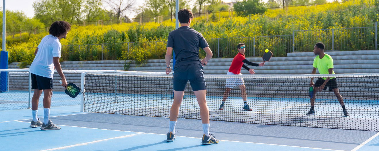 A group of young people playing pickleball outdoors.