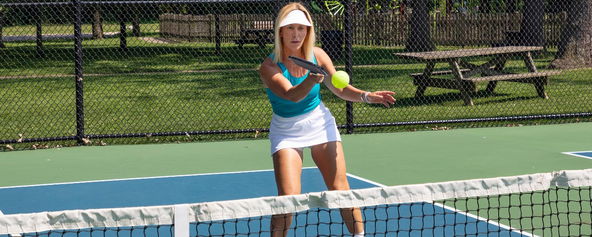 A woman hitting a pickleball out of the air.