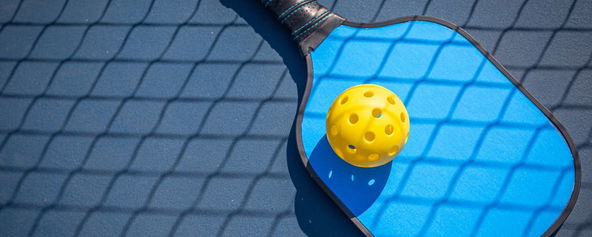 A pickleball paddle and pickleball.