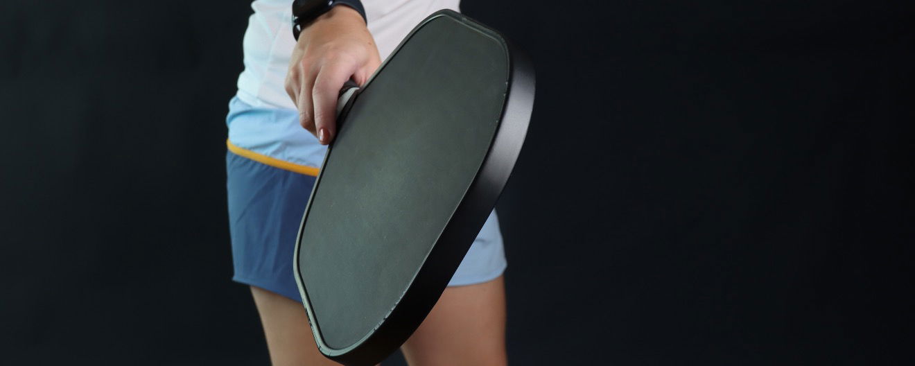A person holding a pickleball paddle.