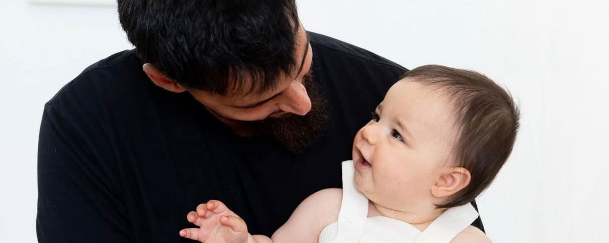 DJ Young holding his baby girl and she is gazing up at him.