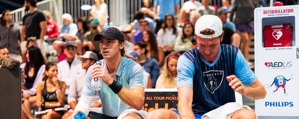 Christian Alshon and Andrei Daescu seated courtside near an AED.