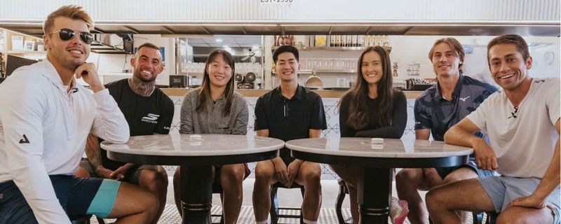 Ben Johns, Tyson McGuffin, Zoey Wang, Anna Bright, Christian Alshon, and Zane Navratil sitting at a coffee shop smiling at the camera.