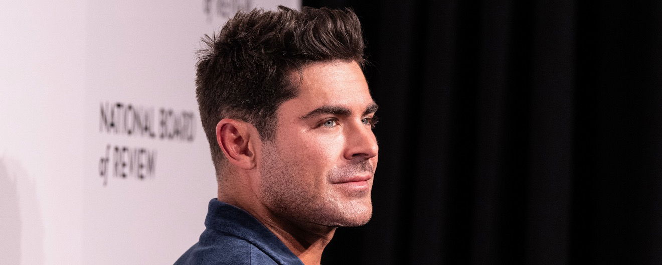 Zac Efron posing for a photo on a red carpet.