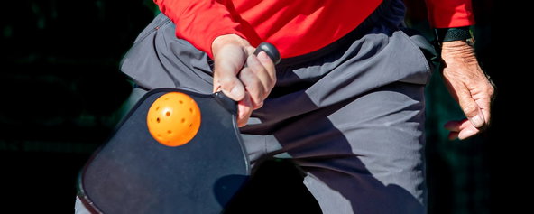 A player holding a pickleball paddle and preparing to hit a shot.