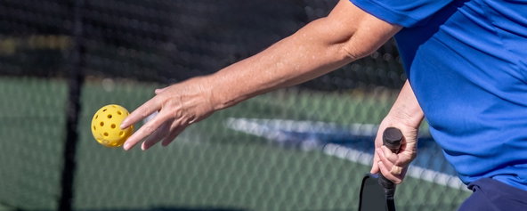 A pickleball player preparing to serve.