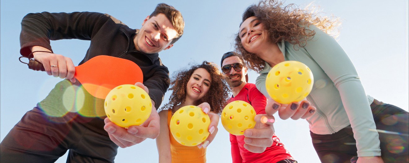 A group of young people with pickleballs in their hands.