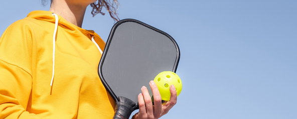 A woman holding a pickleball paddle.