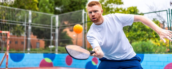 A player preparing to make contact with a pickleball on a court.