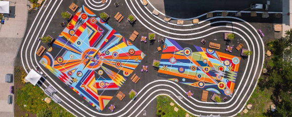 Overhead image of pickleball courts with colorful and geometric murals painted on them.