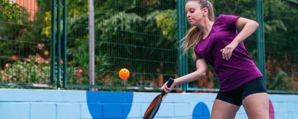 A female pickleball player hitting a pickleball.
