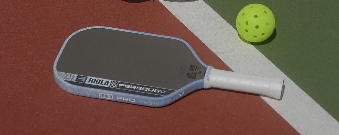 Blue JOOLA pickleball paddle laying on a pickleball court next to a pickleball.