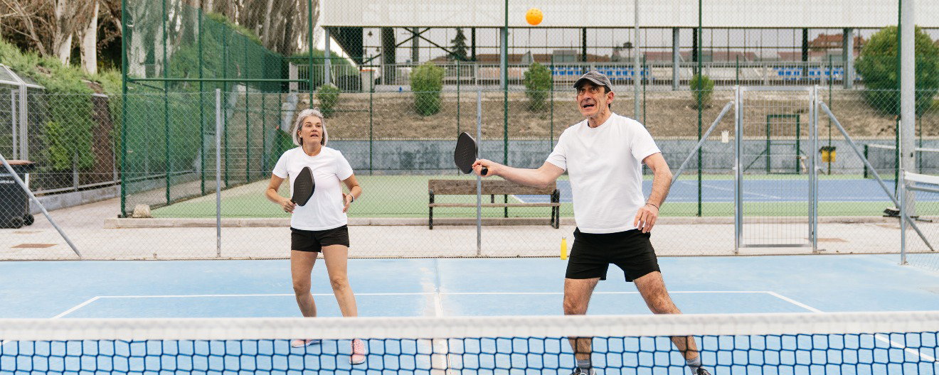Two players on the pickleball court waiting to hit a pickleball.