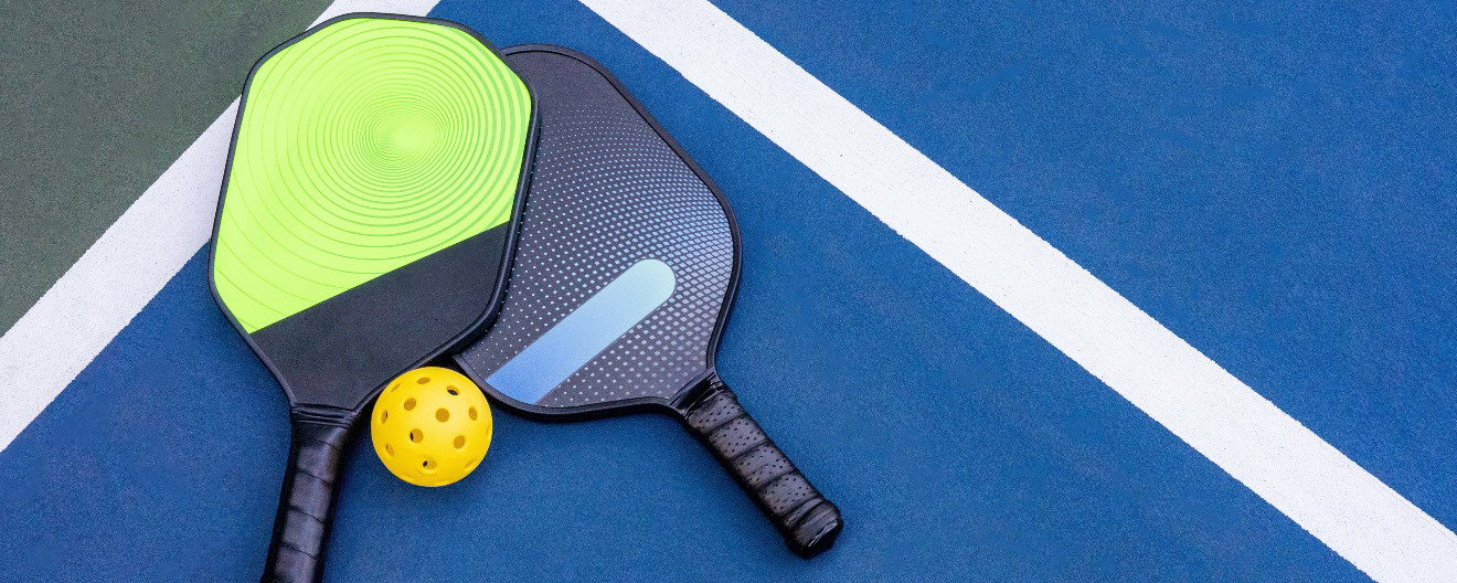Pickleball paddle grit being sanded down with a power sander