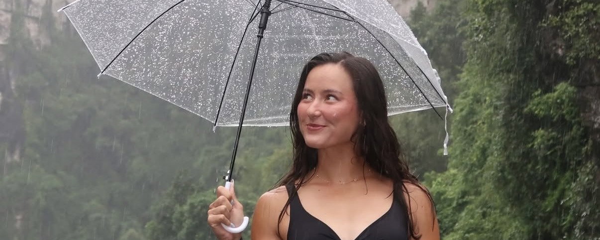 Anna Bright standing with a clear umbrella in the rain.