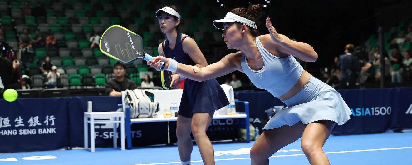 Long wearing a navy dress and Kong wearing a baby blue outfit playing pro pickleball